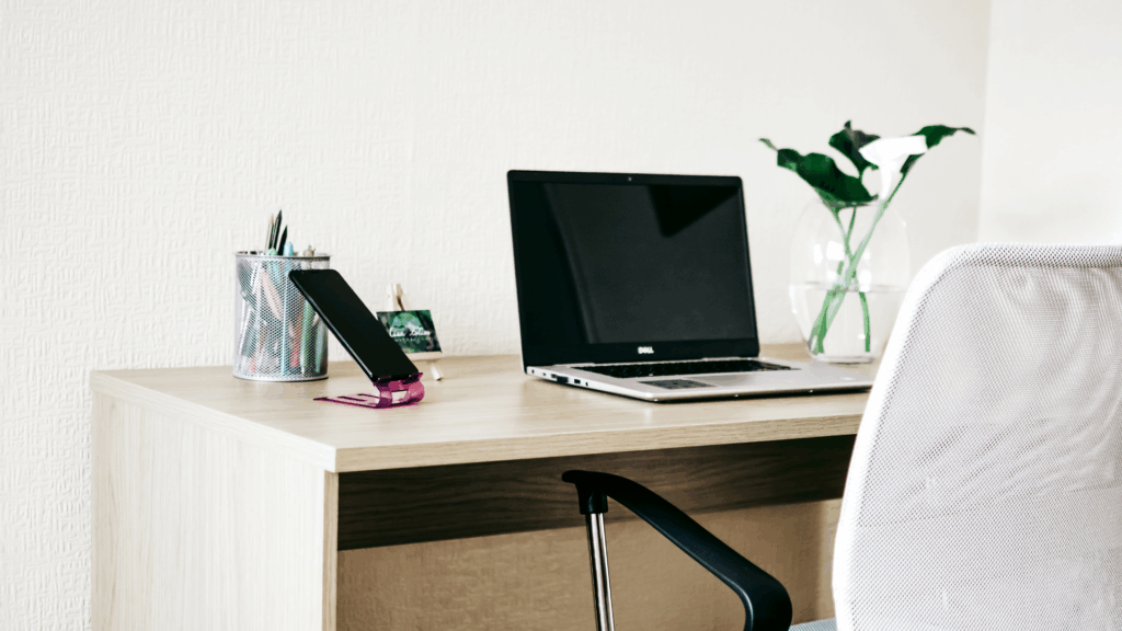 Un poste de travail avec un bureau et une chaise. Un ordinateur et un téléphone sont sur le bureau.